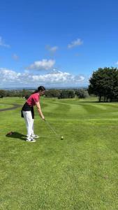 a woman hitting a golf ball on a golf course at Conker's Lodge on Ashbury Resort, Dartmoor Devon in Okehampton