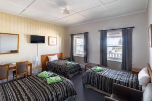 麦克唐奈港The Victoria Hotel的有两张床和一张书桌的酒店房间 更多18张照片
