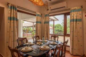 a dining room with a table and chairs and a large window at The White Villa- A Luxurious stay rooted in tradition in Jorhāt