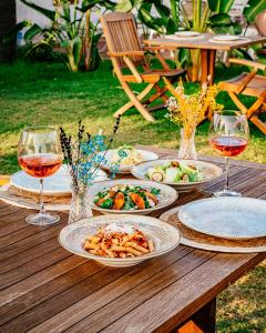 a wooden table with plates of food and wine glasses at Sirius Mİ Sun Paradise Hotel Çeşme in Çeşme
