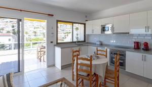 a kitchen with a table and chairs and a kitchen with white cabinets at Cliff View Terrace By Dream Homes Tenerife in Puerto de Santiago +16 photos