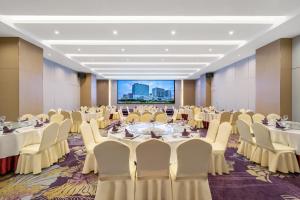 a conference room with tables and chairs and a projection screen at Pearl River International Hotel - Canmetro line 11 YiJing Lu station in Guangzhou