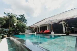 a swimming pool in front of a villa at Maylie Bali Villa & Bungalows in Canggu