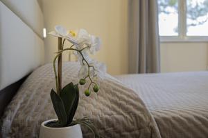 a white flower in a vase sitting on a bed at Grande Albergo in Sestri Levante