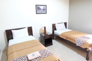 a room with two beds and a night stand at Ndalem Suratin Guesthouse in Yogyakarta