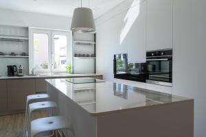 a white kitchen with a counter and stools at Villa Kortus Luxury modern villa near Petram Resort, beach 700m and Adriatic golf resort in Savudrija