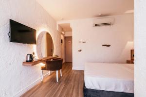 a bedroom with a bed and a desk and a tv at Sirius Mİ Sun Paradise Hotel Çeşme in Çeşme