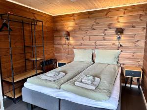 a bed in a wooden room with two towels on it at Bjørnfjell Mountain Lodge in Alta