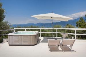 a hot tub and two chairs and an umbrella at Villa Roby-Loft a Torri del Benaco in Torri del Benaco