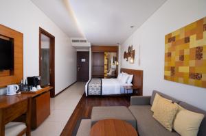 a hotel room with a bed and a couch at MERUSAKA Nusa Dua in Nusa Dua