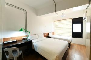 a hotel room with two beds and a desk at Travelbee Seaside Inn in Tagbilaran City