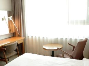 a room with a bed and a desk and a table at Grabel Hotel Jeju in Jeju