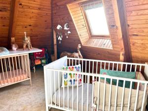 a nursery with a crib and a window and wooden walls at Appartement une chambre plus une chambre bébé ou enfant trois ans à la campagne au calme in Cléguérec