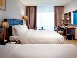 a hotel room with two beds and a desk at Grabel Hotel Jeju in Jeju