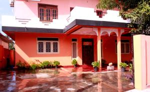 une maison rouge avec de l'eau de pluie devant elle dans l'établissement D'Villa Guest House, à Jaffna