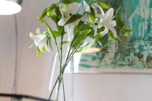 a glass vase with white flowers in it at Apartment Design - Terrazzo, vista lago mozzafiato in Caslano +30 photos