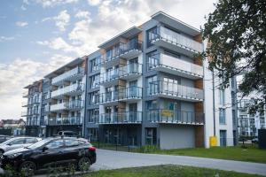 ein Mehrfamilienhaus mit davor geparkten Autos in der Unterkunft Apartament Bałtycka & Bike Room in Kołobrzeg
