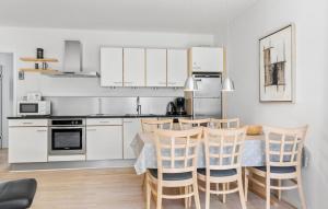 een keuken met witte kasten en een tafel en stoelen bij Gudhjem Søpark Lejl 25 in Gudhjem
