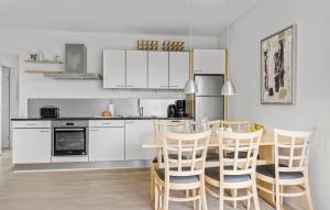 Una cocina con gabinetes blancos y una mesa y sillas. en Gudhjem Søpark Lejl 16, en Gudhjem 21 fotos más