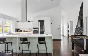 a kitchen with a island with bar stools at 3 Bedroom Amazing Home In Rødby in Rødby