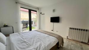 ein weißes Schlafzimmer mit einem Bett und einem Fenster in der Unterkunft Vila Blanc in Costinești