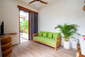 a green couch in a living room with a plant at Dive into Bliss - Brand New Seminyak Villa with Private Pool in Seminyak