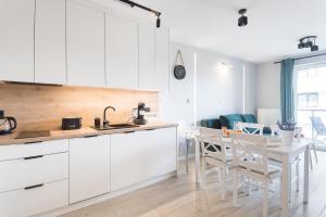 eine Küche mit weißen Schränken und einem Tisch und Stühlen in der Unterkunft Apartament Bałtycka & Bike Room in Kołobrzeg