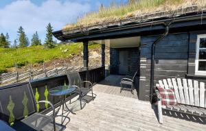 Una terraza con sillas y una mesa y un edificio con techo de césped. en Amazing Home In Sjusjøen With Sauna, en Sjusjøen 10 fotos más