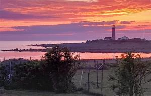a sunset over the ocean with a lighthouse in the distance at 3 Bedroom Gorgeous Apartment In Borhaug in Borhaug