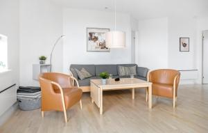 Una sala de estar con un sofá, una mesa y sillas. en Gudhjem Søpark Lejl 2, en Gudhjem