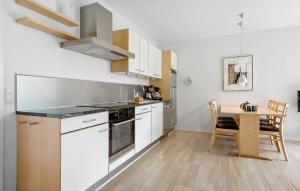 a kitchen with white cabinets and a table with a dining room at Gudhjem Søpark Lejl 23 in Gudhjem