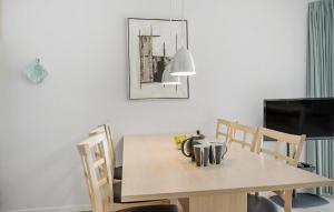 a dining room table with chairs and a television at Gudhjem Søpark Lejl 23 in Gudhjem