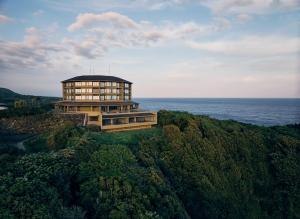 a building on top of a hill next to the ocean at samana hotel Yakushima in Yakushima