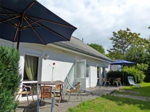 a patio with a table and chairs and an umbrella at Ferienhof Nonnevitzer Strand, Typ B in Dranske
