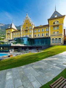 a large yellow building with a green lawn in front of it at Grand Hotel Billia in Saint Vincent