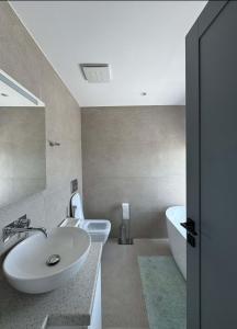 a bathroom with a sink and a tub and a toilet at Penthouse Sea view Apartments in Sarandë +18 photos