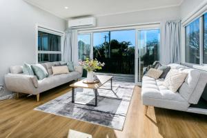 un soggiorno con due divani e un tavolo di Eden St Lukes Cozy Accommodation ad Auckland