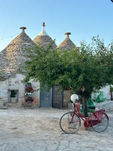 a red bike parked in front of a building with a tree at Trulli Arborea in Alberobello