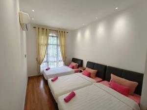 クチンにあるJk Romance House 20Pax 6Carparksのピンクの枕が付いたベッド3台が備わる客室です。