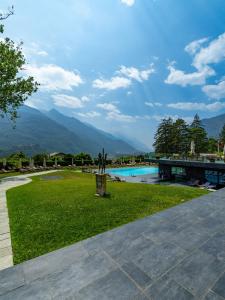 a park with a pool and mountains in the background at Grand Hotel Billia in Saint Vincent