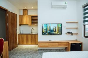 a kitchen and a living room with a tv on a wall at Gala Hotel & Apartment in Hai Phong