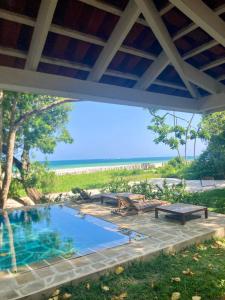 a swimming pool with picnic tables and the beach at Mawimbi Cottage in Ukunda