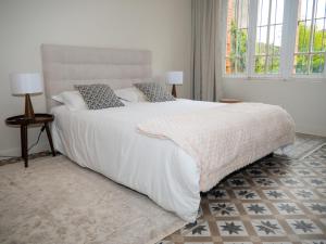 a bedroom with a large white bed with two windows at La chambre du soleil in Lézat-sur-Lèze +6 photos