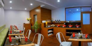 a dining room with tables and chairs and a kitchen at TreeHouse Neptune Inn in Panaji