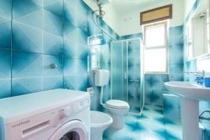 ein blau gefliestes Badezimmer mit einer Waschmaschine darin in der Unterkunft Sisters` house by BarbarHouse in Marina di Mancaversa