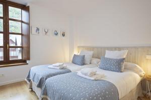 una camera da letto con due letti con asciugamani sopra di Luderna - Apartamento Aiguestortes a Vielha