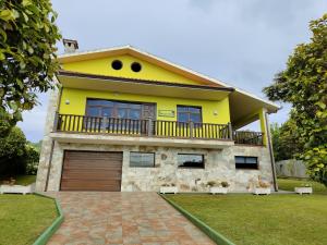 a yellow house with a balcony and a driveway at Ruxidoira, una ventana al Atlántico in Valdoviño