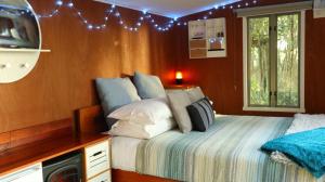 a bedroom with a bed and a television and lights at Fantail Bush Chalet and Hot Tub in Parakakau