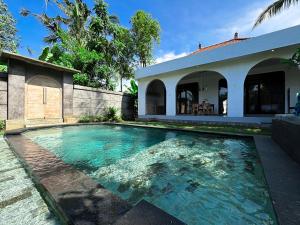 a swimming pool in front of a house at Pradnya Villa in Ubud