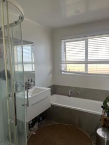 a bathroom with a tub and a sink and a shower at Beach house with a pool in Waihi Beach